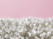 Cubos de açúcar branco sobre fundo rosa . — Fotografia de Stock