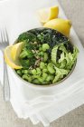 Vários vegetais verdes fatiados em saladeira com limão . — Fotografia de Stock