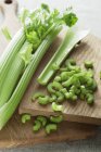Head of celery on wooden chopping board with cut slices. — Stock Photo