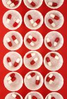 Vista superior de vasos de medicina de papel com cápsulas de drogas vermelhas e brancas . — Fotografia de Stock