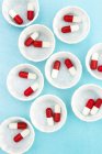 Vista dall'alto di vasi medicinali di carta con capsule di droga rosse e bianche . — Foto stock