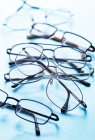 Close-up of various pairs of eyeglasses on blue surface. — Stock Photo
