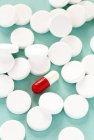 Круглые белые таблетки, окружающие овальный красный и белый капсулы . — стоковое фото