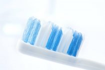 Weiße und blaue Zahnbürste vor schlichtem Hintergrund. — Stockfoto
