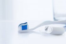 Toothbrush with toothpaste and dental floss against white background. — Stock Photo