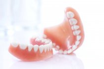 Prótesis dentales sobre mesa sobre fondo blanco . - foto de stock