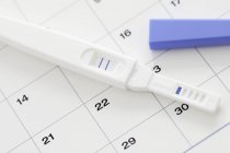 Pregnancy test showing positive result and calendar. — Stock Photo