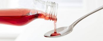 Cough syrup pouring onto spoon on white background, studio shot. — Stock Photo