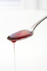 Cough syrup dripping from spoon on white background, studio shot. — Stock Photo