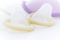 Male and female condoms on white background, studio shot. — Stock Photo