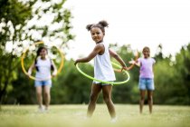 Mädchen im Grundschulalter spielen im Sommerpark mit Hula-Hoop-Reifen. — Stockfoto