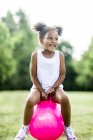 Дошкільнята дівчина підстрибує на надувному бункері в парку і сміється . — стокове фото