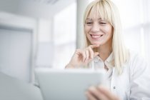 Female doctor using digital tablet and smiling with hand on chin. — Stock Photo