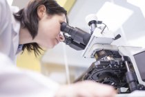 Технік-лаборант жіночий використовуючи мікроскоп в лабораторії. — стокове фото