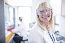 Scienziata donna con occhiali protettivi e sorridente . — Foto stock