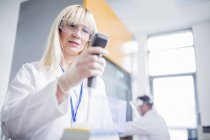 Female scientist wearing protective goggles and using device. — Stock Photo
