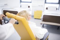 Cropped view of doctor pushing female patient in hospital chair. — Stock Photo