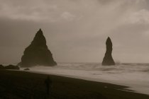 Formazione rocciosa sulla riva dell'acqua al crepuscolo, Reynisdrangar, Vik, Islanda . — Foto stock
