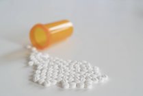 Tabletten, die aus einer gelben Plastikflasche auf weißem Hintergrund austreten. — Stockfoto