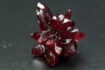Mineralstein aus rotem Kristall auf dem Tisch, Nahaufnahme. — Stockfoto
