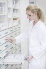 Farmacista donna in cerca di medicinali in cassettiera in farmacia
. — Foto stock