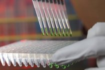 Close-up of multipipette sampling liquid into tube rack in laboratory. — Stock Photo