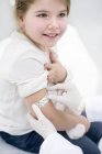 Doctor sticking plaster on little girl arm after injection in medical clinic. — Stock Photo