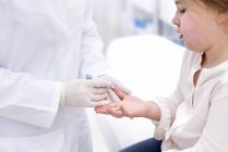Bambina avendo dito puntura test in clinica medica . — Foto stock