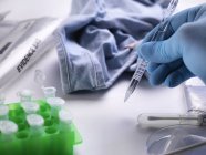 Cientista forense a recolher amostras de cabelo para testes de ADN a partir de roupas da cena do crime . — Fotografia de Stock