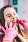 Ortodoncista femenina arreglando frenos dentales de niña en la clínica . - foto de stock