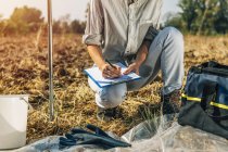 Female agronomist taking notes in field of soil. — Stock Photo