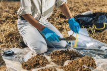 Agronomist putting soil with garden shovel in soil sample bag. — Stock Photo