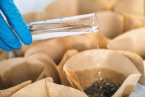 Close-up of biologist pouring water into containers with soil samples. — Stock Photo