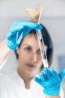 Cientista feminina em laboratório olhando para frasco de vidro com amostras dissolvidas de solo . — Fotografia de Stock