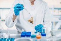Mid section of scientist in laboratory mixing samples of soil with reagent. — Stock Photo