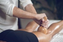 Крупним планом чоловічого масажиста з використанням дерев'яних інструментів на жінку в той час як антицелюлітний медтерапія. — стокове фото