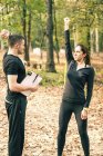 Donna che lavora con la banda di resistenza e istruttore di fitness spiegando allenamento tricipiti
. — Foto stock