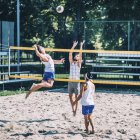 Jugadores de voleibol playa golpeando y bloqueando la pelota en la red mientras juego . - foto de stock