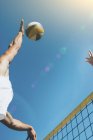 Low angle view of beach volleyball players hitting ball at net. — Stock Photo