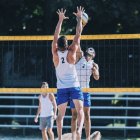 Beach volleyball players blocking at net while game. — Stock Photo