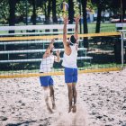 Beach volleyball players blocking at net while game. — Stock Photo