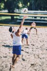Male beach volleyball players in action with ball at net. — Stock Photo