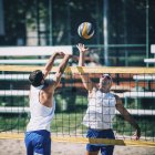 Beach volleyball players in action with ball at net. — Stock Photo
