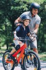 Дідусь і онук катаються разом на роликових ковзанах і велосипеді в парку . — стокове фото