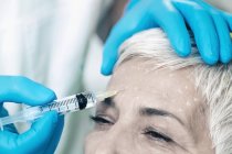 Reife Frau erhält Botox-Injektion in Stirn in Kosmetologie-Klinik. — Stockfoto