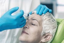 Зрелая женщина получает инъекцию ботокса в лоб в косметологической клинике . — стоковое фото