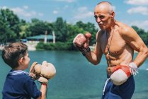 Дедушка и внук занимаются боксом на открытом воздухе . — стоковое фото