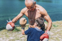 Nonno e nipote boxe in riva al lago all'aperto . — Foto stock
