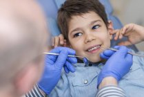 Menino da idade elementar sorrindo enquanto faz check-up dentário . — Fotografia de Stock