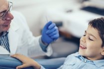 Garçon d'âge primaire ayant un examen dentaire avec un médecin masculin . — Photo de stock